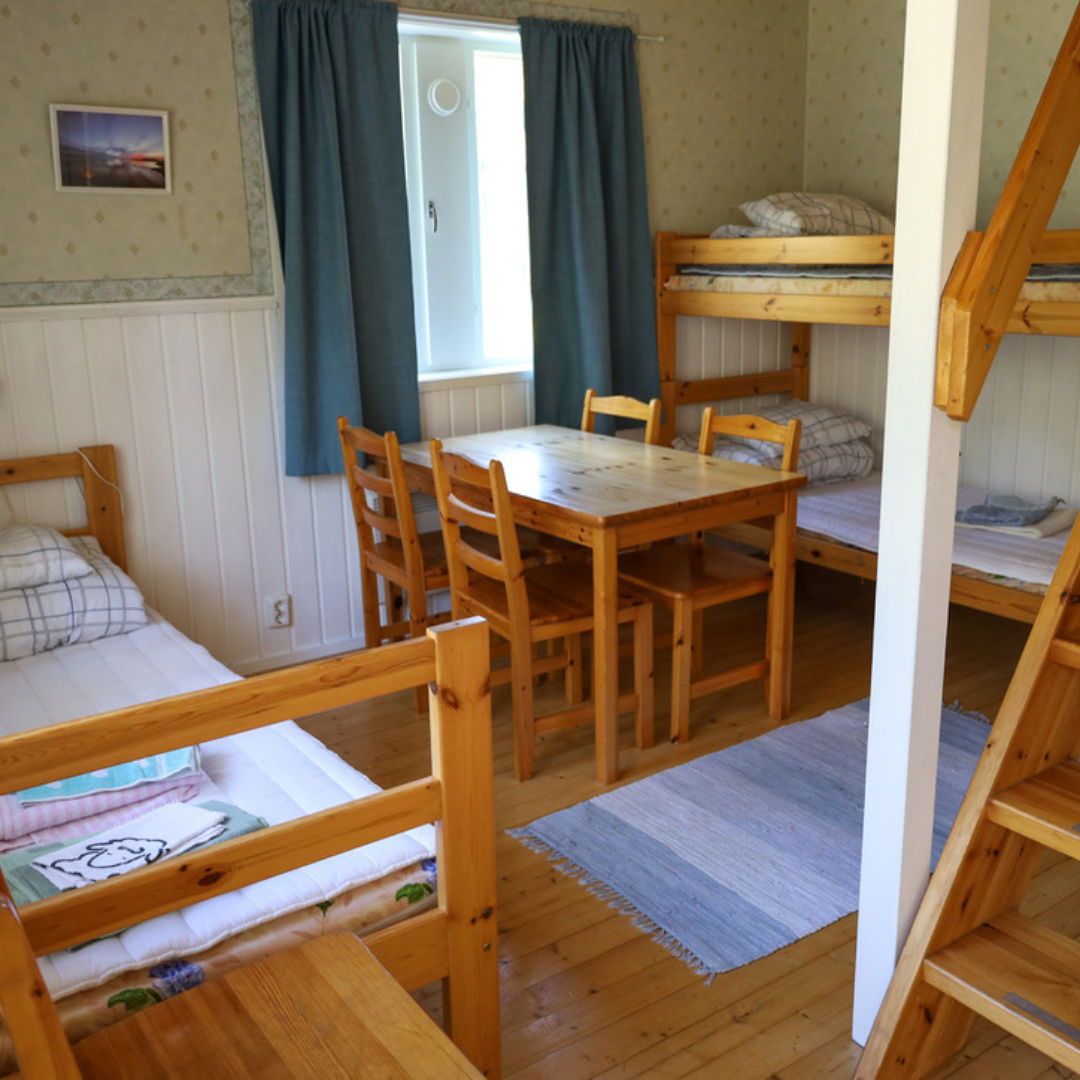 Inredning i lägenhet på Gästhuset Kilstrand – träbord, stolar och flera sängar