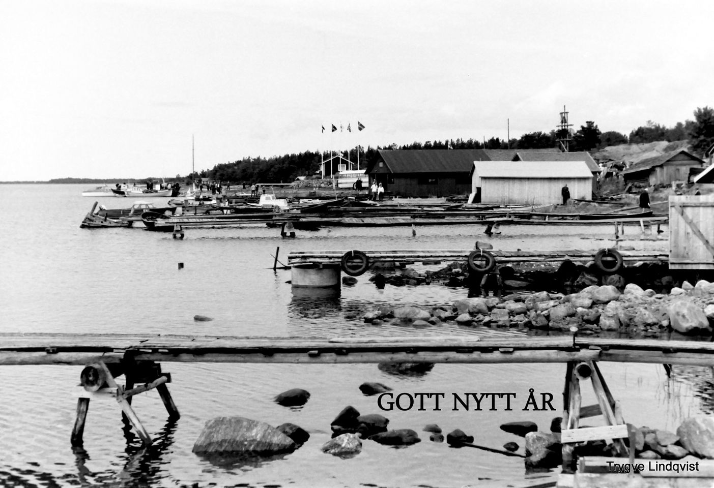 Svartvit bild av bryggor, båtar och strandbodar vid Kilviken